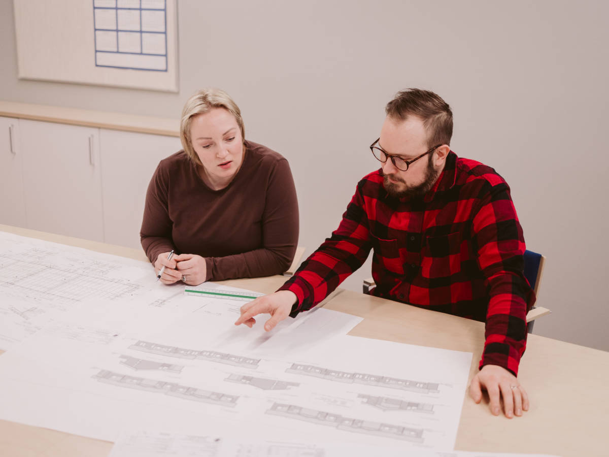 Kaksi teknisen suunnittelun opiskelijaa tutkivat yhdessä rakennuksen piirustuksia yhdessä pöydän ääressä.